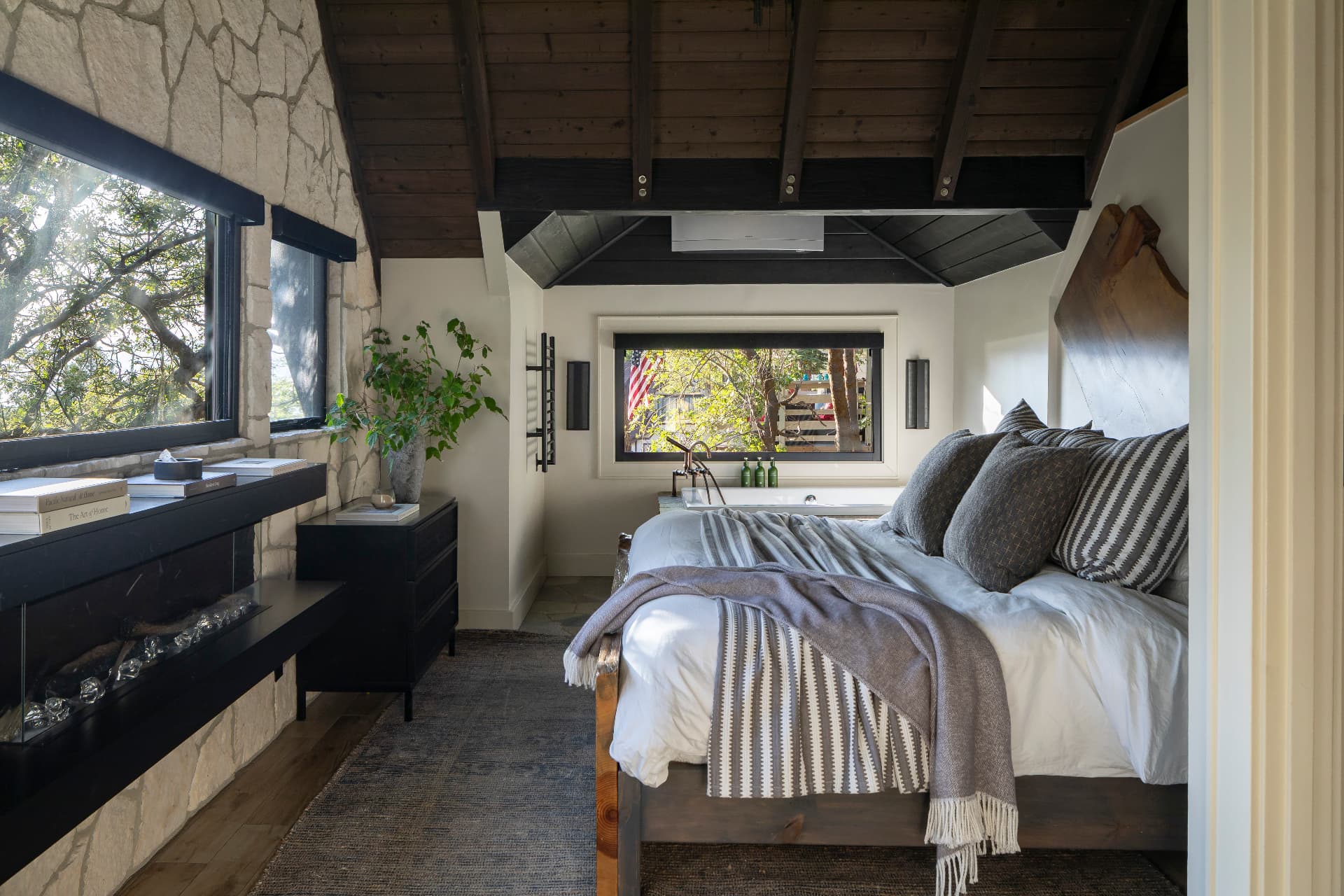 Primary suite with linear fireplace and windows into the trees